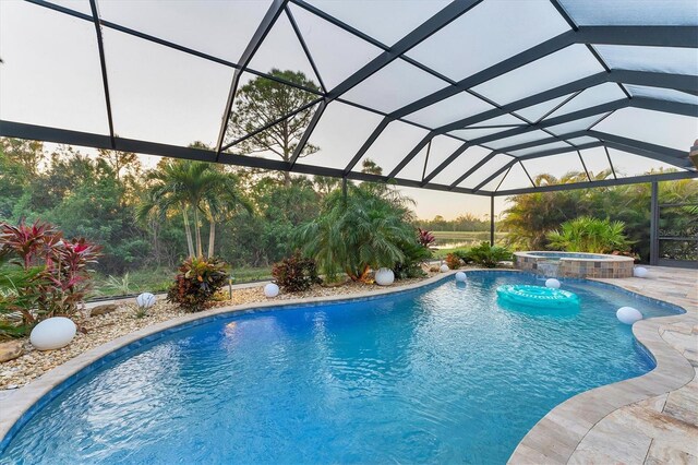 view of swimming pool featuring an in ground hot tub, glass enclosure, and a patio area