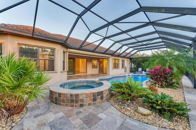 view of swimming pool featuring glass enclosure, an in ground hot tub, and a patio