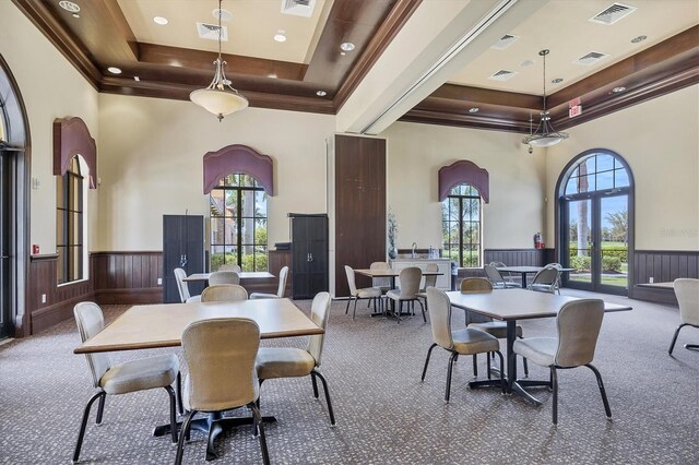 dining room with a raised ceiling, a wealth of natural light, carpet flooring, and a high ceiling