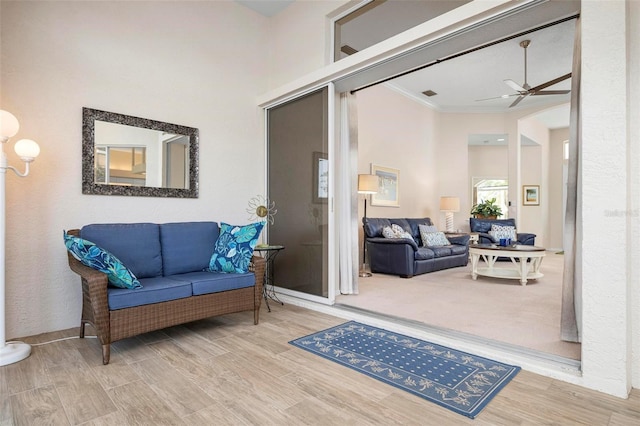 sitting room with hardwood / wood-style flooring, ceiling fan, and crown molding