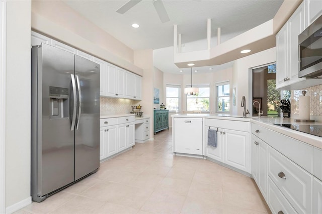 kitchen with decorative backsplash, kitchen peninsula, stainless steel appliances, sink, and white cabinets