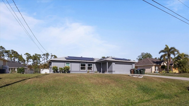 ranch-style house with a front yard, solar panels, and a garage