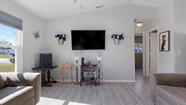 living room featuring lofted ceiling and light hardwood / wood-style flooring