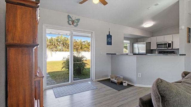 doorway featuring ceiling fan, light hardwood / wood-style flooring, and vaulted ceiling