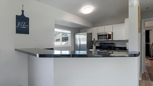 kitchen with white cabinetry, kitchen peninsula, wood-type flooring, lofted ceiling, and appliances with stainless steel finishes