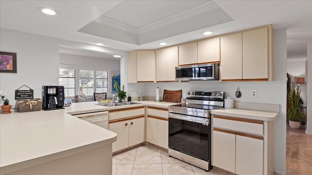 kitchen featuring kitchen peninsula, stainless steel appliances, a raised ceiling, crown molding, and cream cabinets