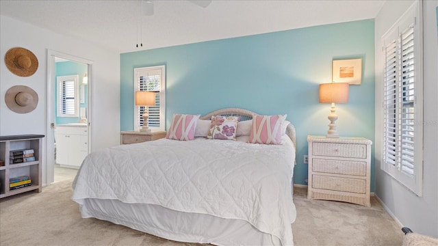 bedroom with ensuite bathroom, ceiling fan, and light colored carpet