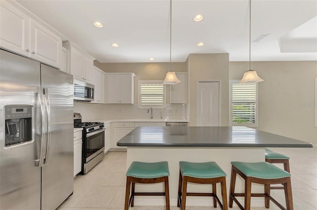 kitchen featuring a kitchen island, a kitchen bar, white cabinetry, and appliances with stainless steel finishes