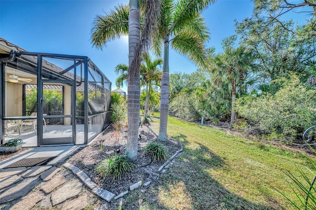 view of yard featuring a patio, ceiling fan, and a lanai