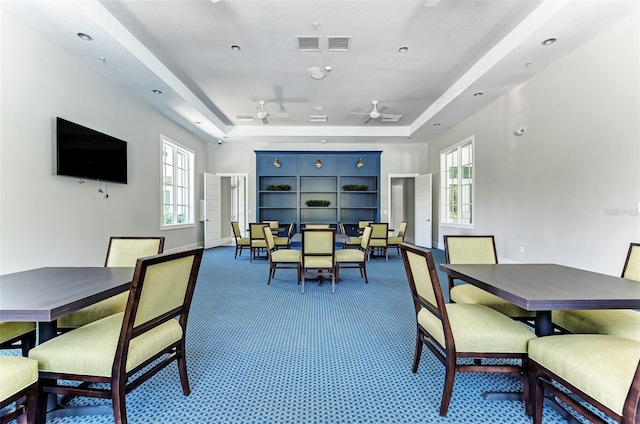 dining room with a wealth of natural light, a tray ceiling, and ceiling fan