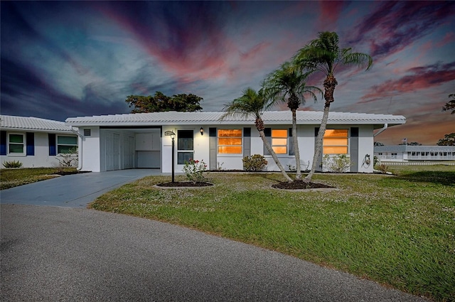 single story home featuring a carport and a lawn