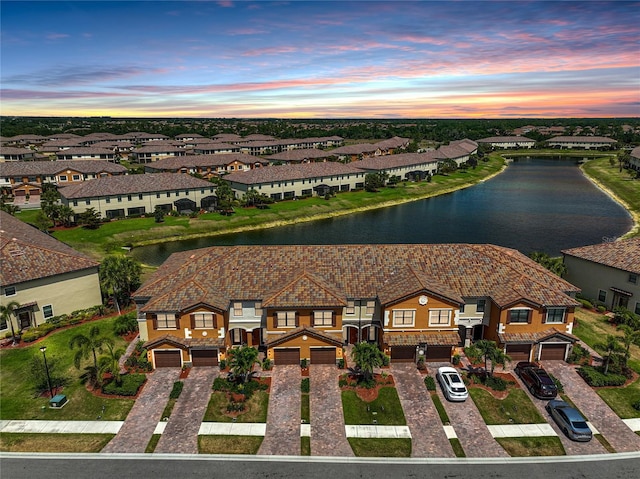 aerial view at dusk featuring a water view