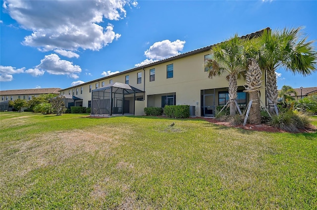 back of property featuring a lawn and glass enclosure