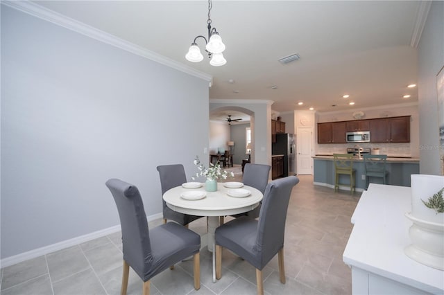 tiled dining space with ceiling fan with notable chandelier and ornamental molding