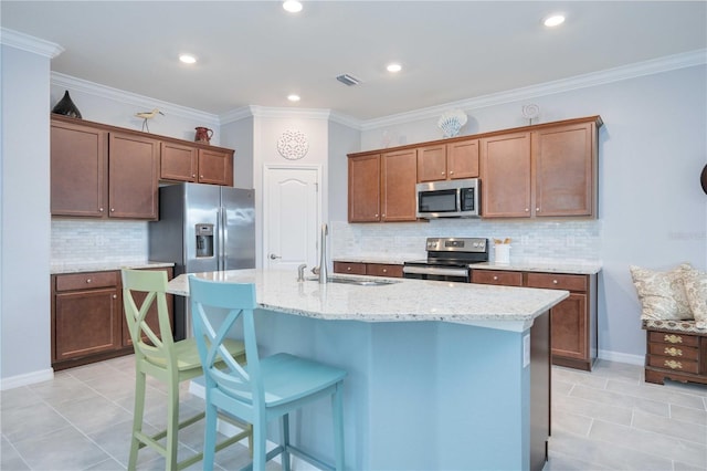 kitchen with backsplash, sink, an island with sink, and appliances with stainless steel finishes