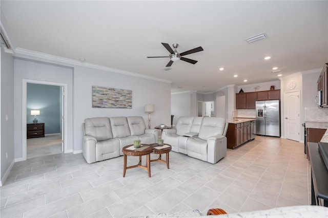 tiled living room with ceiling fan, sink, and crown molding