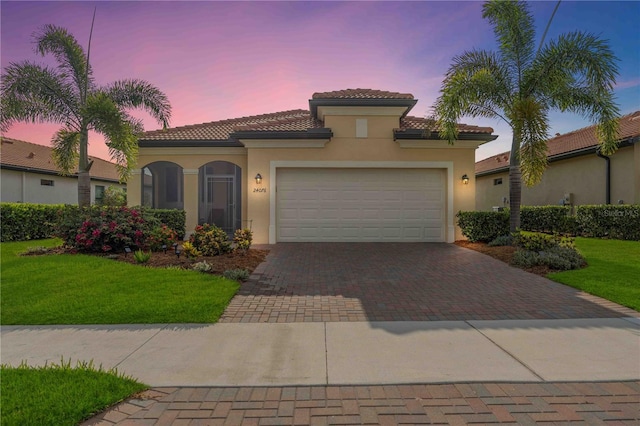 mediterranean / spanish house with a lawn and a garage