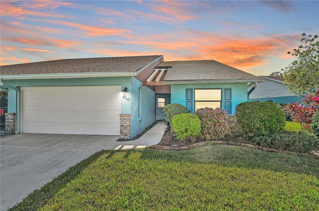 ranch-style house with a garage and a lawn