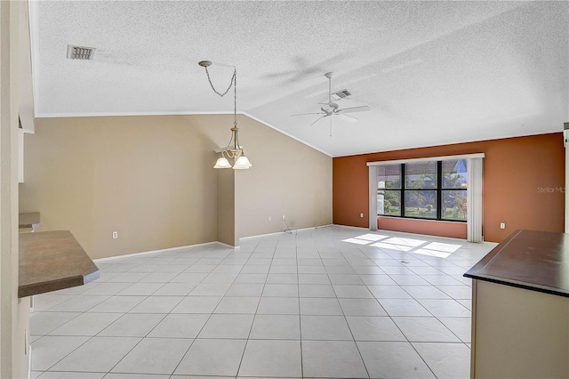 unfurnished living room with ceiling fan with notable chandelier, light tile patterned flooring, and vaulted ceiling