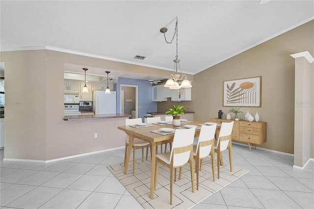 tiled dining space with lofted ceiling, ceiling fan, a textured ceiling, and ornamental molding