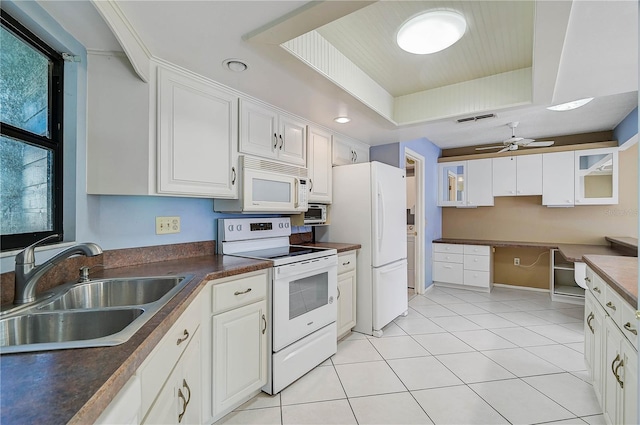 kitchen with white appliances, a raised ceiling, ceiling fan, sink, and white cabinets