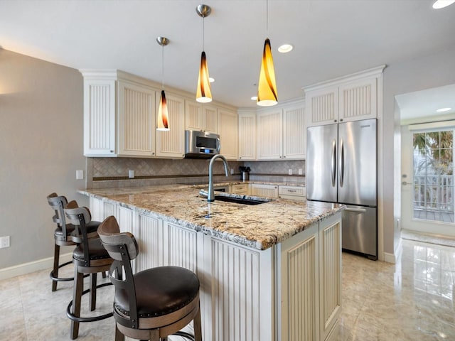 kitchen with light stone countertops, sink, tasteful backsplash, pendant lighting, and appliances with stainless steel finishes