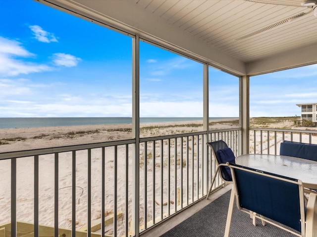 unfurnished sunroom featuring a view of the beach and a water view