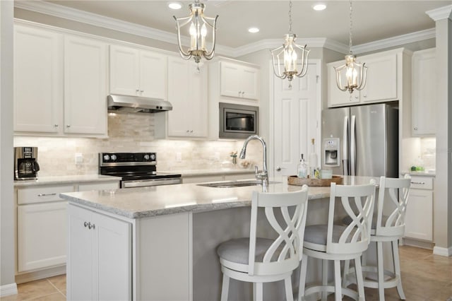 kitchen with appliances with stainless steel finishes, sink, light tile patterned floors, white cabinetry, and an island with sink