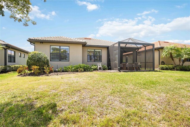 back of property with a yard and glass enclosure