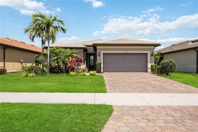 view of front of home with stucco siding, a front lawn, a garage, a tiled roof, and decorative driveway