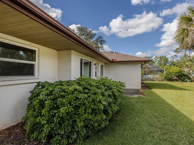 view of side of property featuring a lawn and a lanai