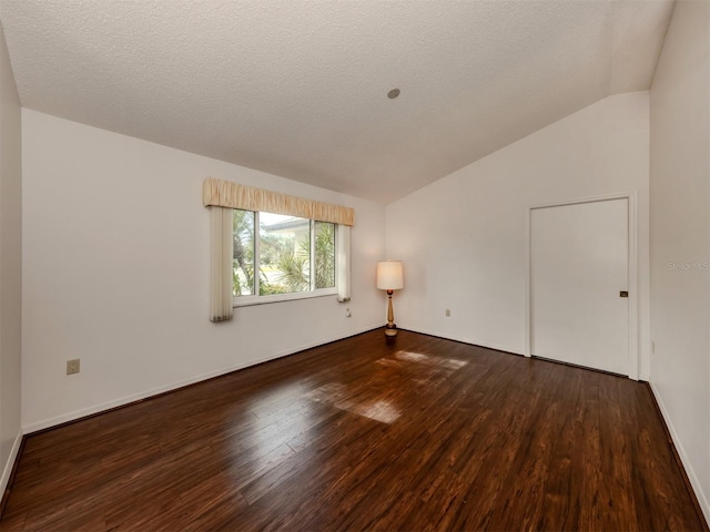 unfurnished room with a textured ceiling, hardwood / wood-style floors, and lofted ceiling