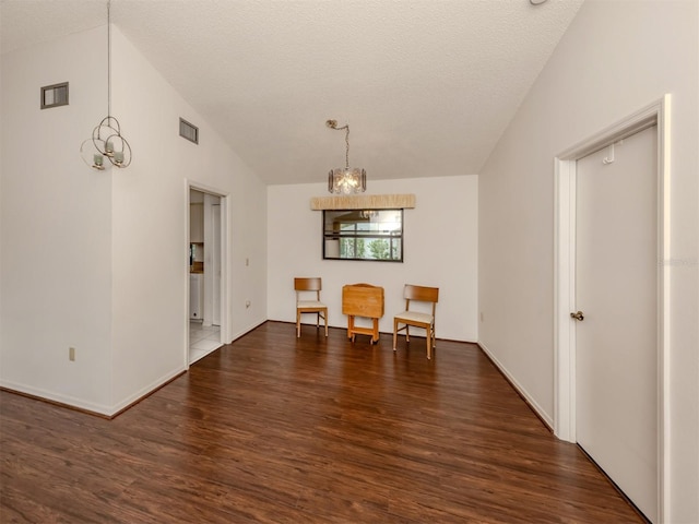 interior space with a textured ceiling, vaulted ceiling, an inviting chandelier, and dark wood-type flooring