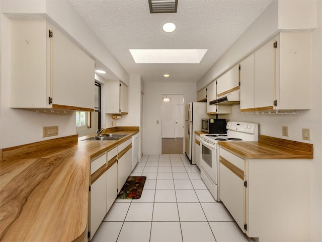 kitchen featuring white appliances, sink, a skylight, a textured ceiling, and white cabinetry