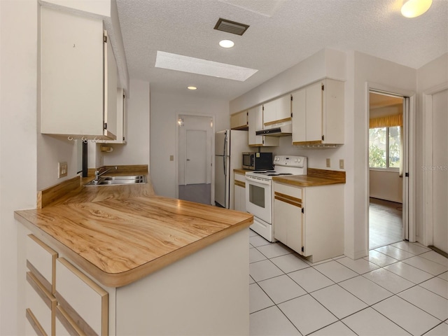 kitchen with a textured ceiling, white appliances, a skylight, and sink