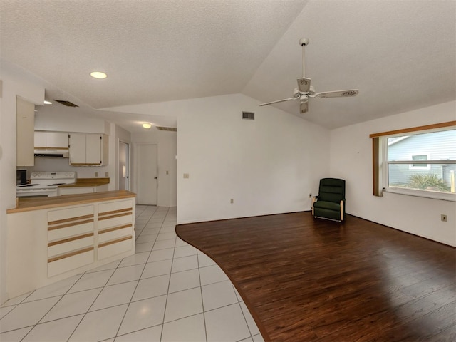 unfurnished living room with ceiling fan, lofted ceiling, a textured ceiling, and light tile patterned floors