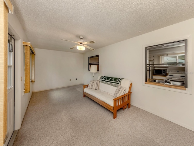 sitting room featuring carpet flooring, ceiling fan, and a textured ceiling