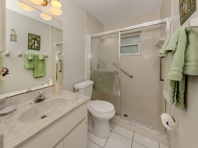 bathroom featuring a textured ceiling, vanity, tile patterned flooring, toilet, and a shower with shower door