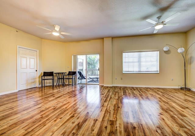 living room featuring ceiling fan, a textured ceiling, and light wood-type flooring