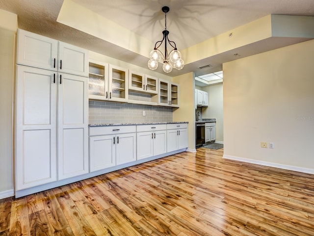 kitchen featuring white cabinets, decorative backsplash, dishwasher, and hanging light fixtures