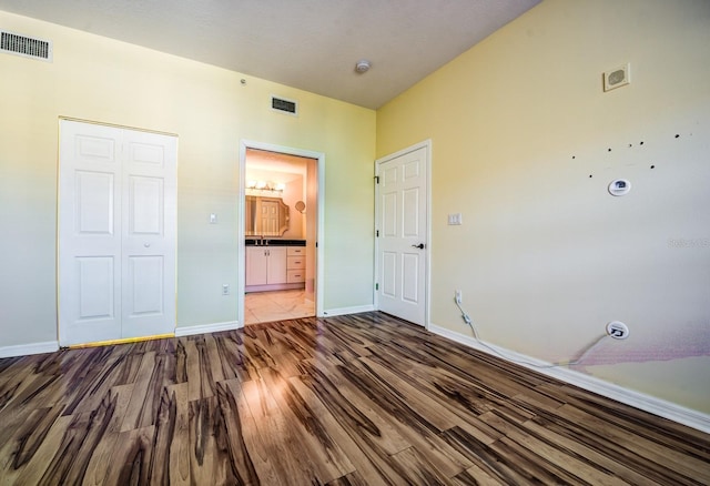 unfurnished bedroom with hardwood / wood-style flooring, connected bathroom, and a closet