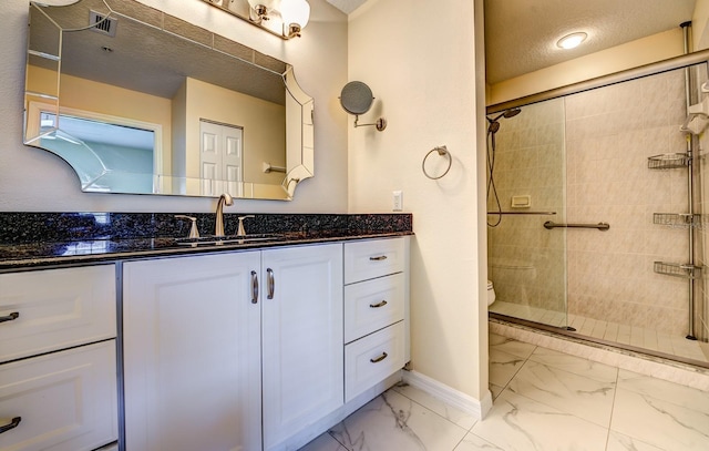 bathroom featuring vanity, toilet, a shower with shower door, and a textured ceiling