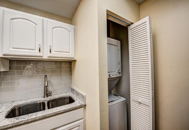 clothes washing area featuring sink and stacked washer / dryer