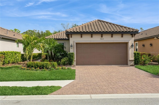 mediterranean / spanish-style home with a garage and a front lawn