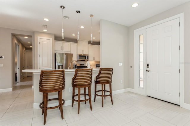 kitchen featuring hanging light fixtures, light tile patterned floors, a breakfast bar, appliances with stainless steel finishes, and sink