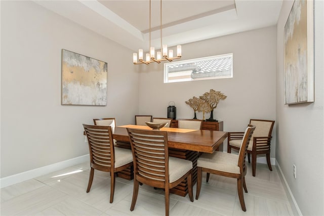 dining space featuring a raised ceiling and a notable chandelier