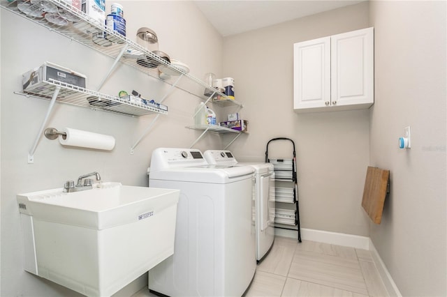 clothes washing area with washing machine and dryer, cabinets, light tile patterned flooring, and sink