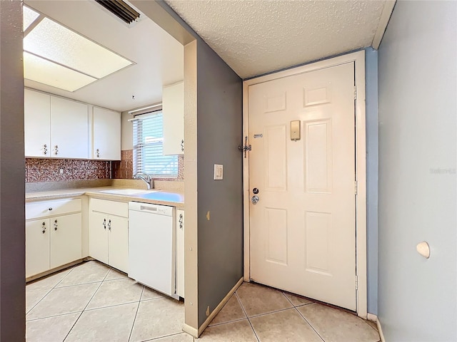 kitchen featuring white cabinets, white dishwasher, sink, and light tile patterned floors