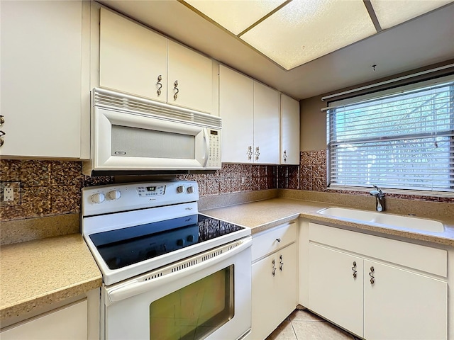 kitchen with light tile patterned floors, sink, white appliances, white cabinets, and decorative backsplash