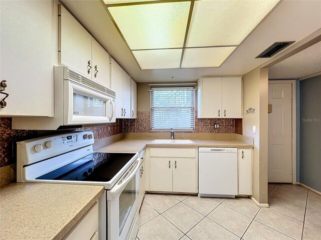 kitchen featuring sink, white appliances, light tile patterned floors, white cabinetry, and tasteful backsplash